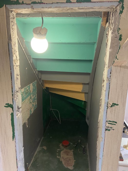 Rivningsarbete av dörrkarm som exponerar råa väggkanter och trapphus.