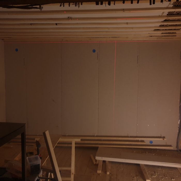 Renovering av rum med nya gipsskivor på väggen och laserlinje som visar ojämnheter.