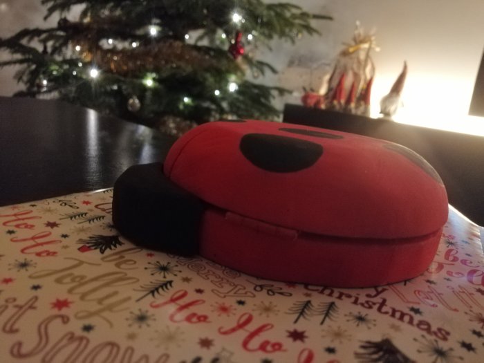 Hemmasnickrad nyckelpiga-skrynkläda framför ett julgran med juldekorationer i bakgrunden.