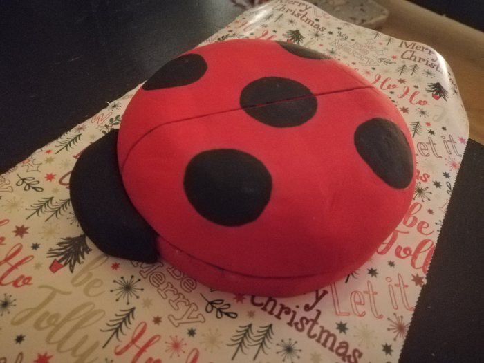 Hemmagjord nyckelpiga i trä på julinslaget papper - ett hemmasnickrat projekt.