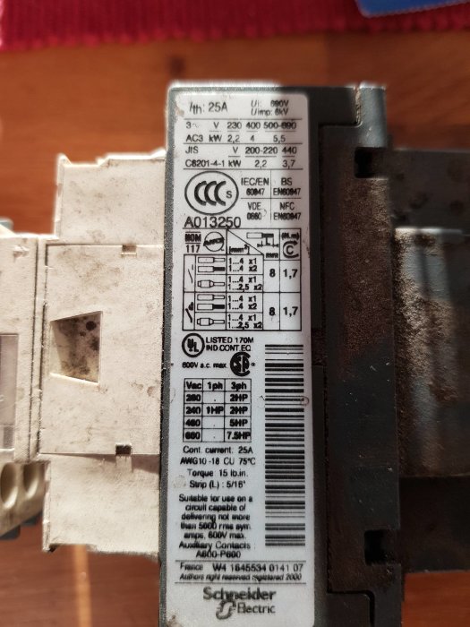 Etikett på en elkomponent med tekniska specifikationer och säkerhetsmärkningar, tillverkad av Schneider Electric.