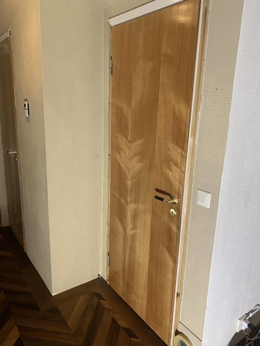 Lackad glasdörr med kulör i en hall under renovering, utan lister vid dörrkarmen.