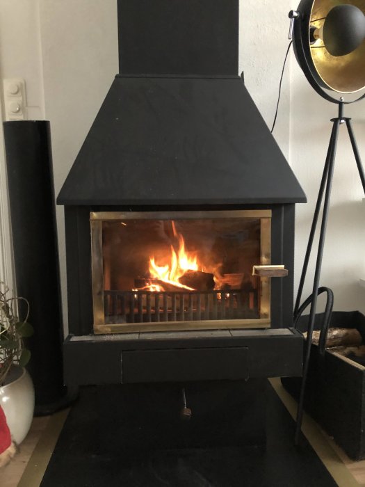 Kamin med öppna spjäll och eld, användare frågar om luftflödesinställningar.