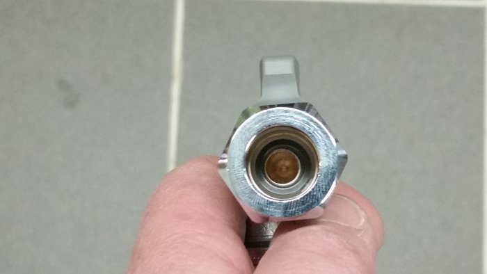 Hand håller en 15mm kulventil från Vatette med synligt litet hål genom ventilen.