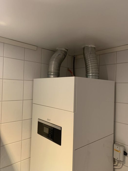 Otillräcklig installation av ventilationsslangar ovanför en vit köksskåp med en inbyggd mikro.