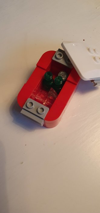 Lego-modell av en röd och vit bil med flaskor byggda av gröna legobitar och dekorationer inuti.