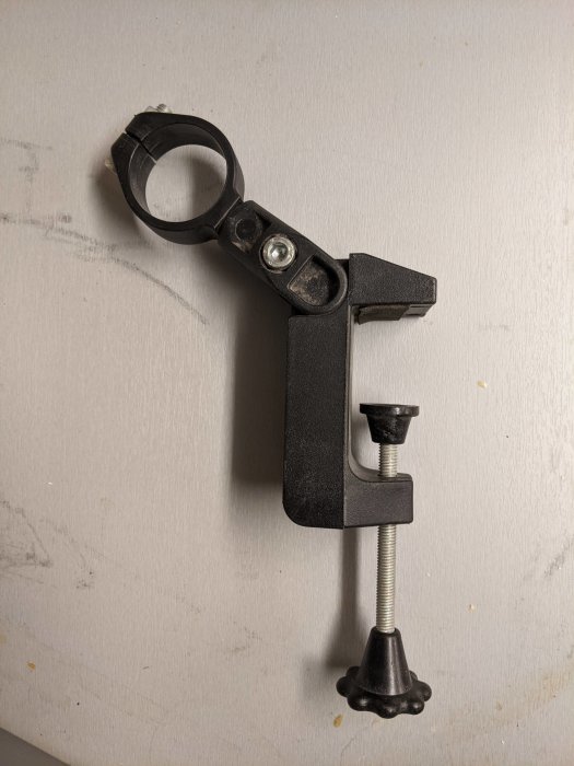 Svart okänd verktygsdel med ring och skruvklämma mot vit bakgrund, ringens diameter 42 mm.