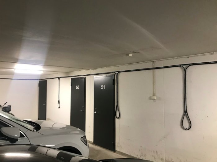 Kabeldragning i källargarage med kabelstegar längs väggen och förberedda kabelöglor för boxar.