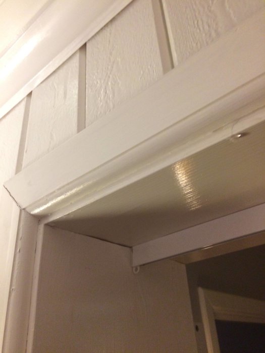 Vattendroppe på ovansidan av en vitmålad dörröppning efter stormregn.