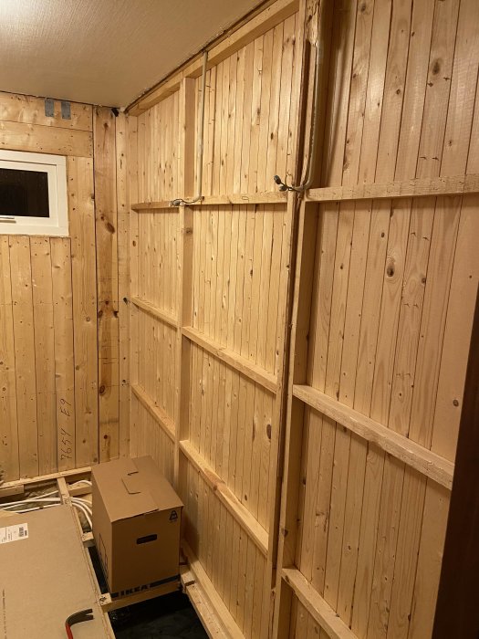 Öppna träreglar i ett pågående badrumsrenoveringsprojekt där rördragning ska döljas, med synliga elledningar.