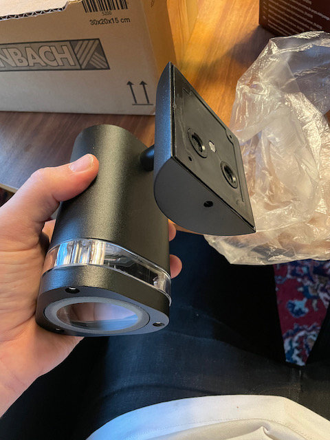 Hand håller en ny utomhuslampa med sladdhål i botten, ämnad för stolpmontering.