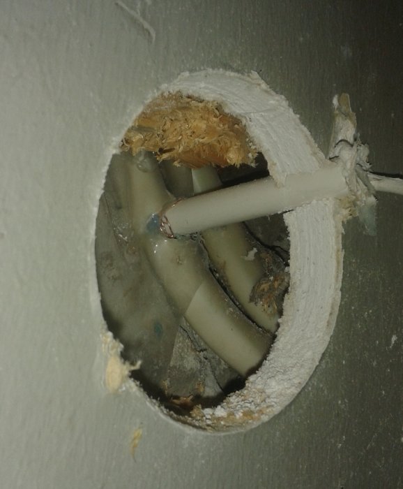 Hål i vägg med skadat VP-rör och kablar, felaktig borrning vid installation av utetempgivare.