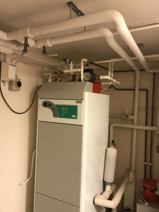 Värmepump CTC EcoHeat och rörinstallationer i ett pannrum, med synlig manometer och expansionskärl.