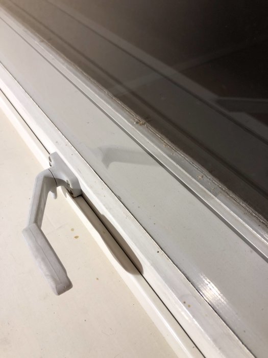 Närbild på ett fönster med gångjärn märkta "Fix", synliga slitage och vibrationsspår.