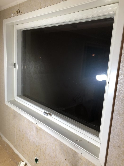 Ett fönster med vita karmar i ett rum, gångjärn märkta med Fix synliga upptill.