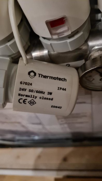 Närbild av ett Thermotech ställdon för golvvärme med specifikationsmärkning.