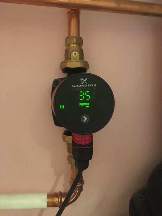 Grundfos cirkulationspump monterad på en kopparledning med synliga inställningsvärden på display.