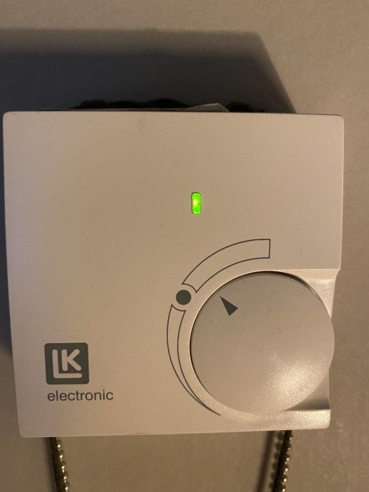 Termostat med en grön lysdiod, logotypen LK electronic och en justeringsknapp.