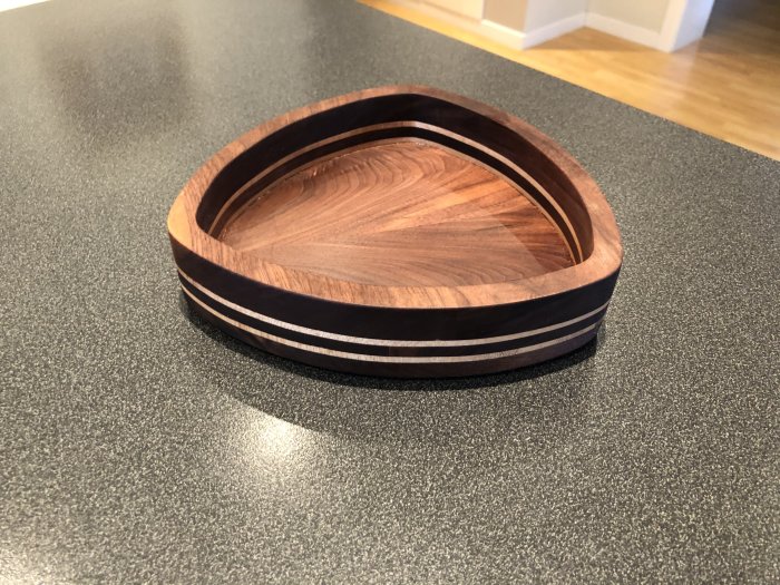 Trekantig skål av valnöt och lönn på en köksbänk.