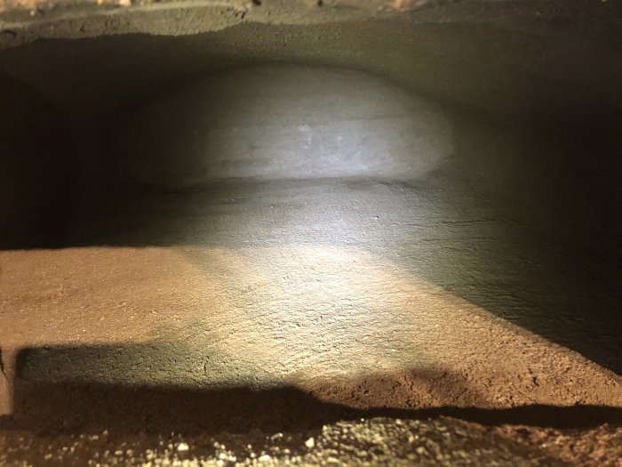 Inuti en nyligen ler-slammat stenugn, skimmer av sand syns på ytan.