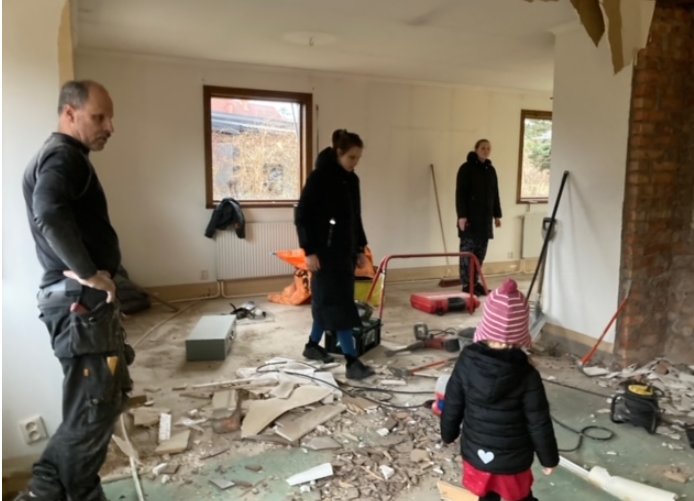 Personer betraktar rivningsarbetet i ett stökigt vardagsrum under husrenovering.