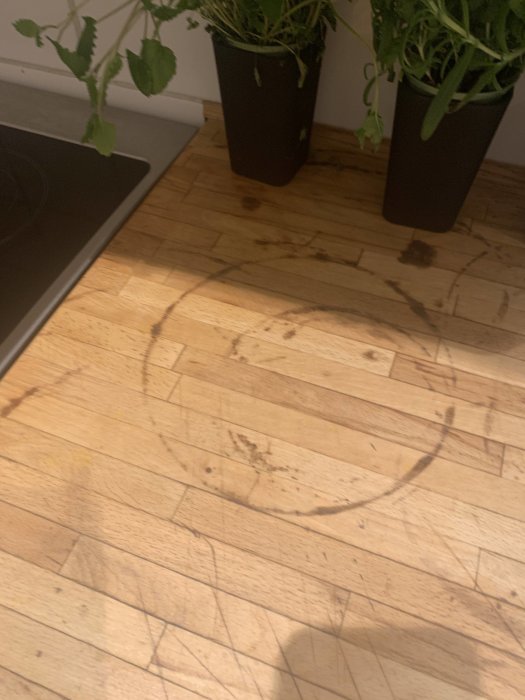 Köksbänk i trä med mörka ringar och repor, antagligen orsakade av varma kastruller.