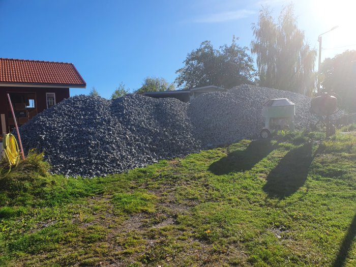 Stor hög med grå isoleringsmaterial från Hasopor på en solig gårdsplan, omgiven av grönska.