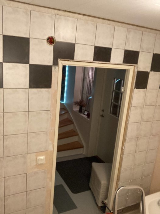 Renoveringsprocess av ett badrum där kakel läggs på äldre väggar med synlig vattenpass och stegar.