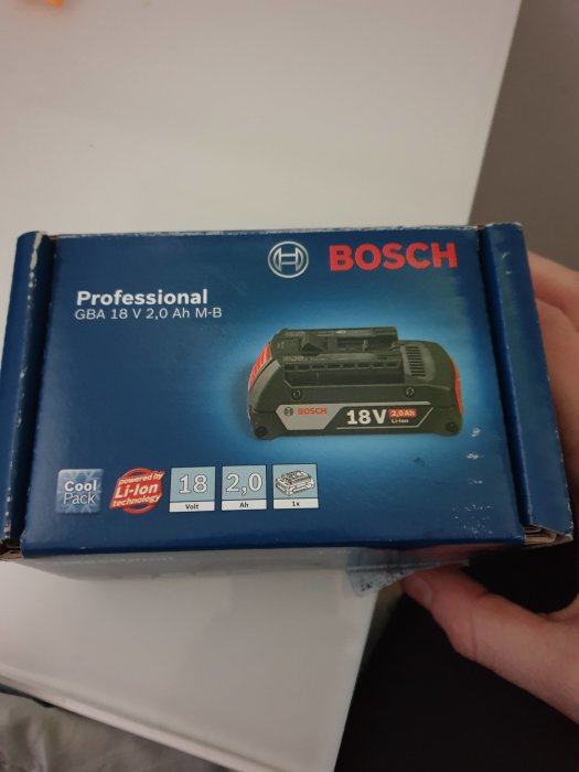 Ny Bosch 18V 2Ah batteri i förpackning hållen av en person.