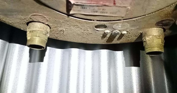 Två mässingsrörgängor med en ytterdiameter på cirka 27.2 mm som sticker ut från en byggkonstruktion.