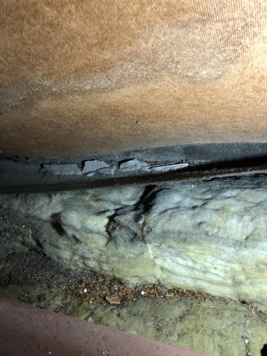 Isolering på vinden med tecken på släppt vindpapp, grus och smutsansamlingar.