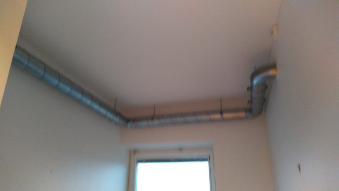 Nyinstallerad fläktkåpa kopplad till ventilationssystem längs tak i rum.