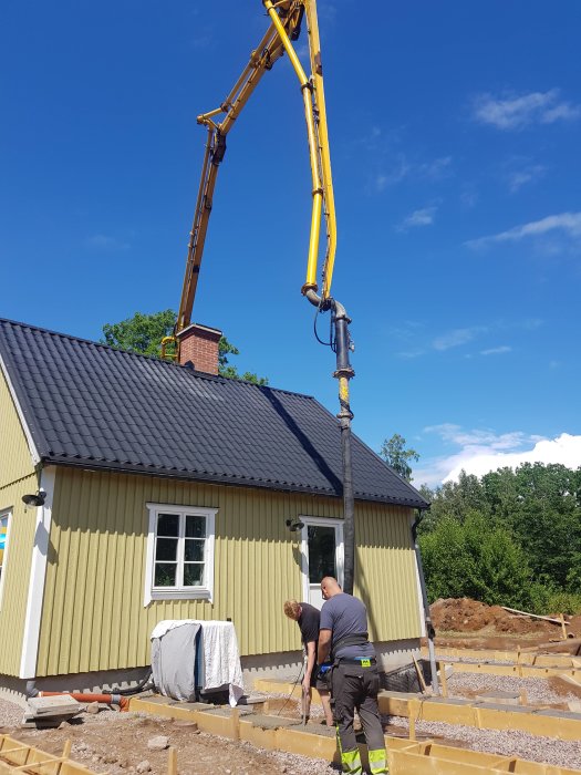 Betong pumpas med hjälp av betongpumpbil vid grundarbete för hus och blivande trädäck.