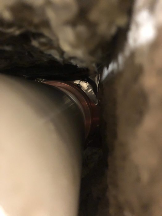 Ventilationsrör anslutet till ett större hål med synlig alutejp och silikon tätningar.