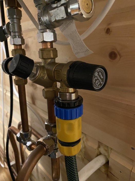 VVS-installation med rör, kopplingar och trädgårdsslang i en fritidsstuga.