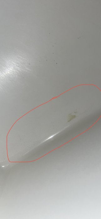 Närbild på ett handfat med en grön fläck och små prickar, omgivet av små sprickor och repor.