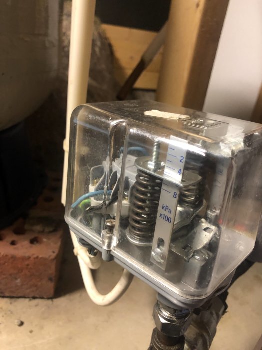 En tryckströmbrytare med skala för inställning av vattentryck, synligt placerad på vatteninstallation.