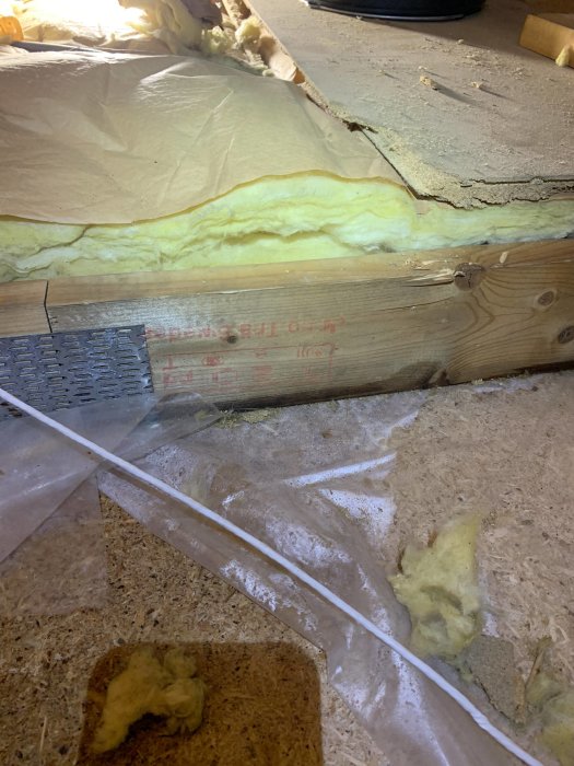 Beskådningsbild av en vind isolerad med mineralull, framträdande fuktfläck på ångspärr och uppbrutna isoleringsplattor.