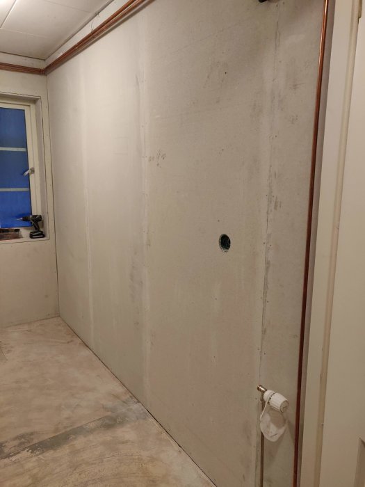 Nyinstallerade fibergipsskivor på vägg i renoveringsprojekt med synlig damm och limrester.