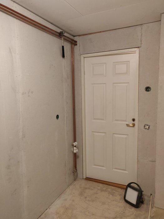 Renoverat rum med nya fibergipsskivor på väggarna, synliga skruvhål och omonterad dörr.