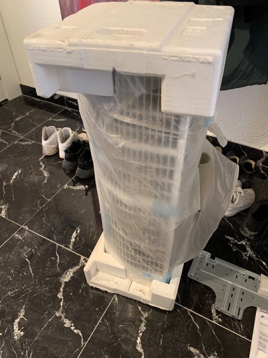 Ny inomhusinverter för uppvärmning och kylning, nästan helt omsluten i skyddande folie och förpackningsmaterial.