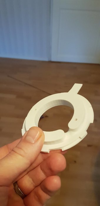 Hand håller ett 3D-printat vitt fäste för Ubiquiti accesspunkt.