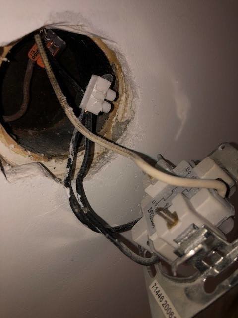 Öppen vägglåda med elinstallation, en strömställare och synliga ledningar; en svart och två vita kopplade till ställaren.