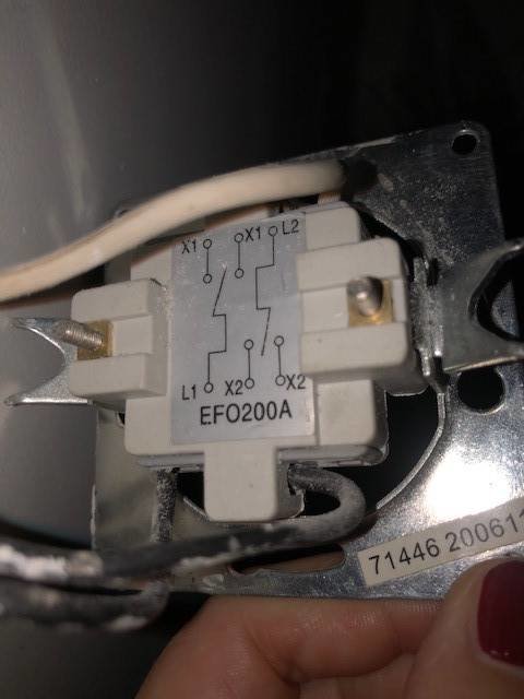 Närbild av en öppen strömställare med ledningar kopplade, synlig schematisk märkning.
