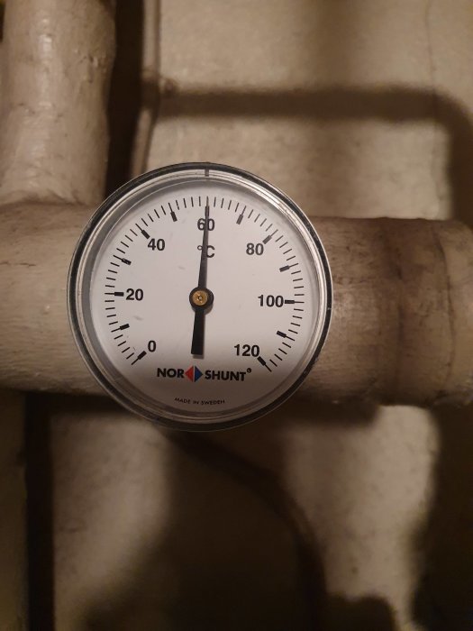 Termometer på varmvattensystem som visar cirka 60 grader Celsius.