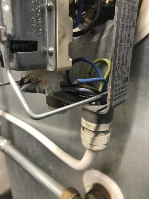 Närbild av en elpatrons anslutningar och kopplingsdiagram, med synliga elektriska ledningar och komponenter.