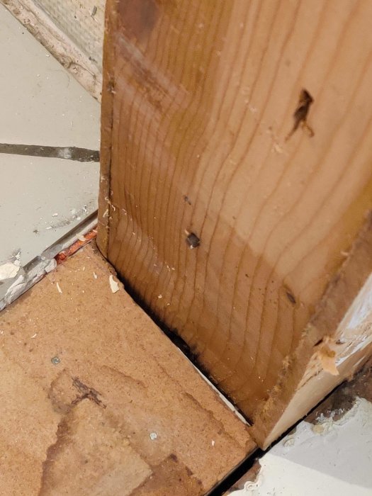 En træregel ved gulv og væg, hvor dørkarmen er fjernet, ses i nærbillede. Diskuteres om den er bærende.