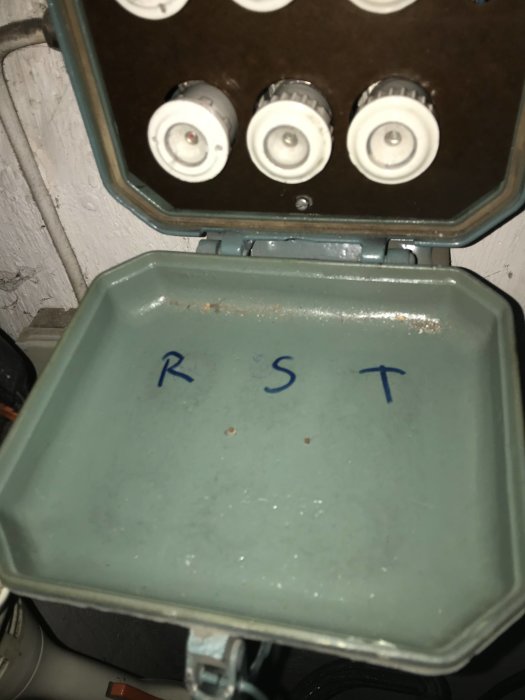 Eluttag med säkringar ovan och bokstäverna R, S, T markerade i blått nedan.