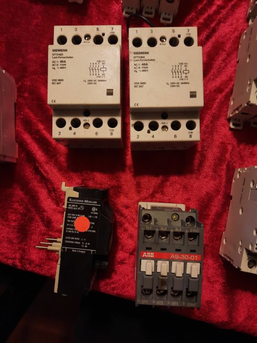 Automatsäkringar och elektriska komponenter från Siemens och ABB på röd bakgrund.