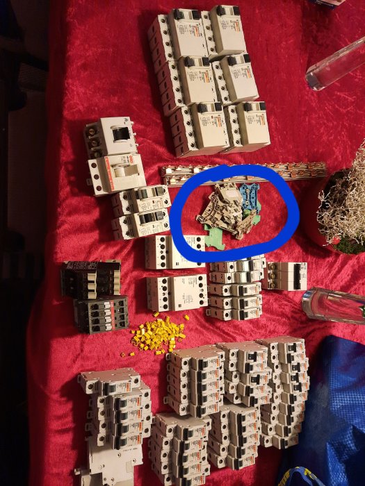 Elektriska komponenter på röd duk med kopplingsplintar inringade i blått.